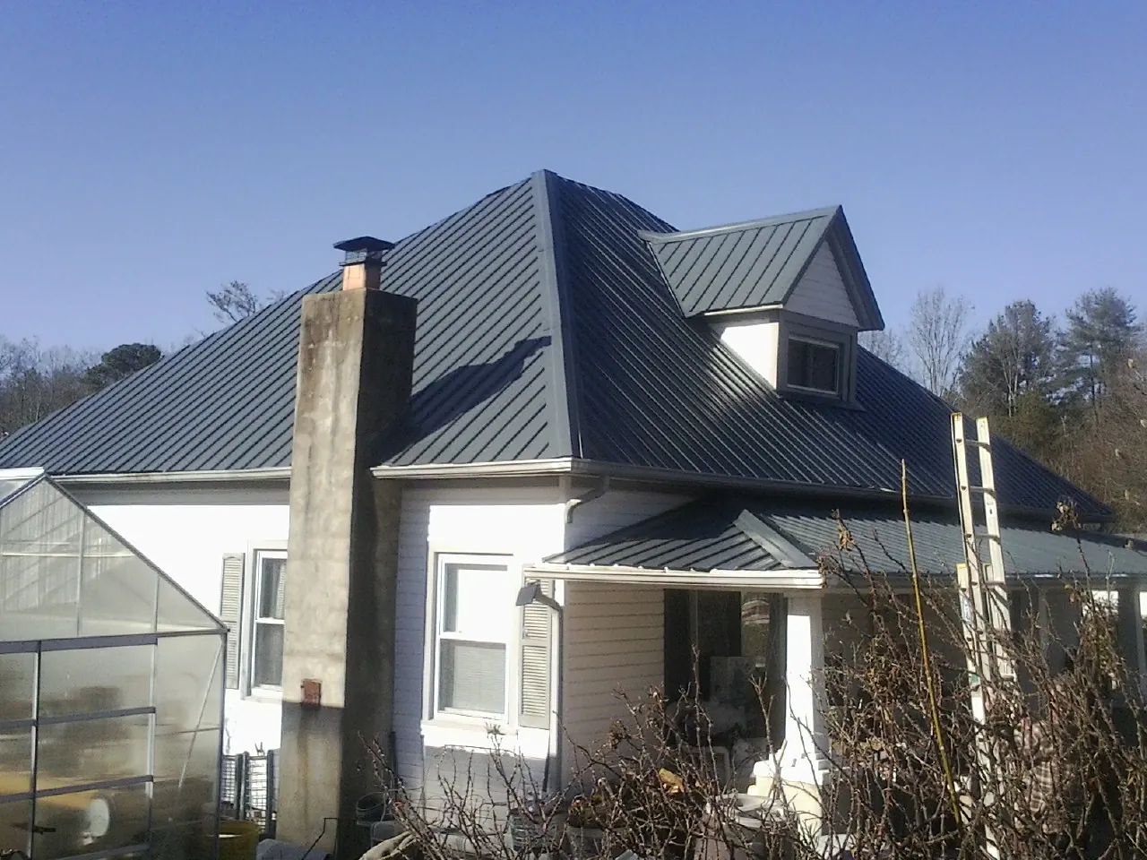 Dark blue standing seam metal roof on a white farmhouse with dormer — Slate & Tile Roof Repair by Roofing Brothers in Barneveld