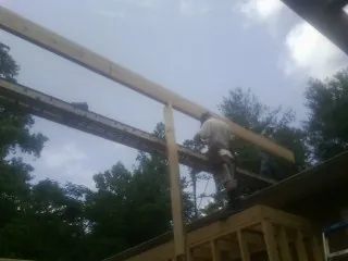 Carpenter setting a ridge beam over a new addition frame — Ice Dam Removal by Roofing Brothers in Barneveld