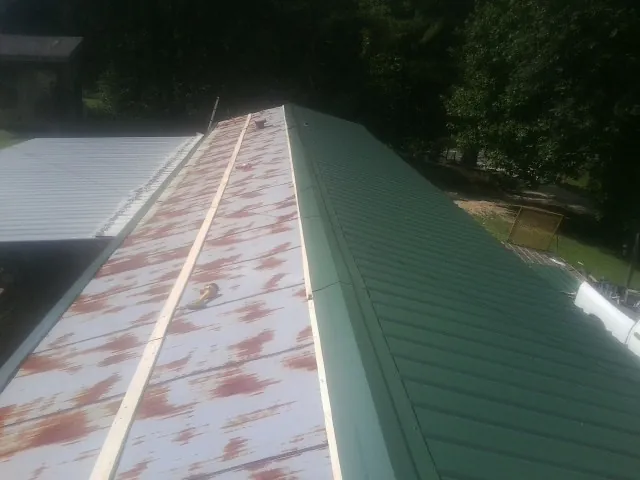 Old rusted panels beside newly installed green metal roofing — Wind Damage Roof Repair by Roofing Brothers in Barneveld
