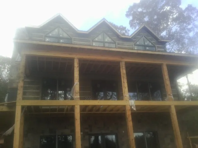 Dormers and porch framing on a large log home under construction — Roof Coating work by our crew in Barneveld