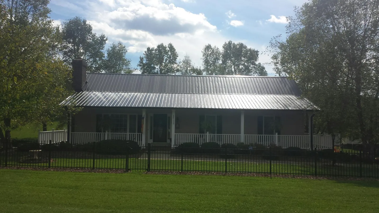 Gray metal roof on a brick ranch with a full width front porch — Gutter Guard Installation work by our crew in Barneveld