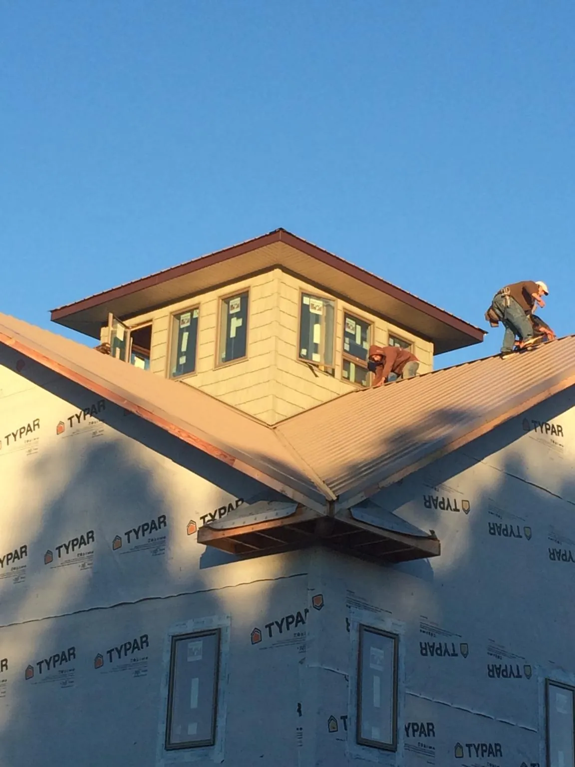 Roofers working around a rooftop cupola on a new metal roof at sunset — Roof Waterproofing in Barneveld by Roofing Brothers